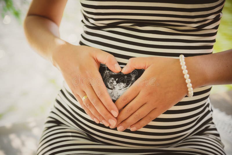 Sluit omhoog portret van gelukkige zwangere vrouw die het beeld van haar toekomstige baby houden bij buik, dient het maken van ha royalty-vrije stock afbeelding Sluit omhoog portret van gelukkige zwangere vrouw die het beeld van haar toekomstige baby houden bij buik, dient het maken van ha royalty-vrije stock afbeelding