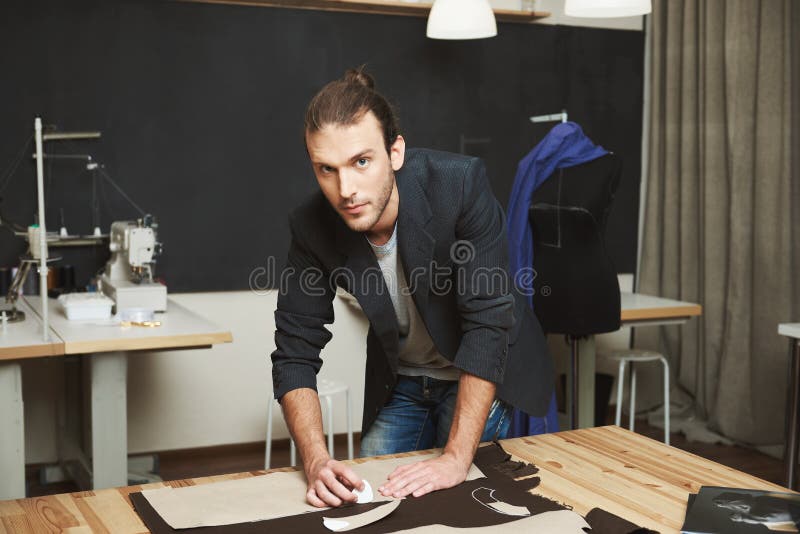 Sluit omhoog portret van het aantrekkelijke rijpe donker-haired Kaukasische mannelijke manierontwerper kijken in camera met ontsp stock fotografie Sluit omhoog portret van het aantrekkelijke rijpe donker-haired Kaukasische mannelijke manierontwerper kijken in camera met ontsp stock fotografie