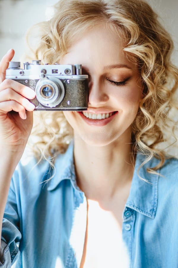 Sluit omhoog portret van mooie blonde jonge vrouw met oude uitstekende camera in haar handen stock fotografie Sluit omhoog portret van mooie blonde jonge vrouw met oude uitstekende camera in haar handen stock fotografie