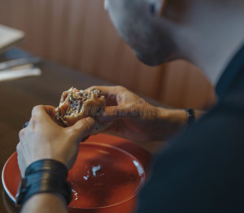 Sluit omhoog van de jonge aantrekkelijke mens die hamburger en frieten eten bij koffie stock fotografie Sluit omhoog van de jonge aantrekkelijke mens die hamburger en frieten eten bij koffie stock fotografie
