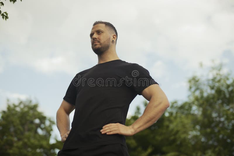 Sluit omhoog van de jonge mens in het zwarte sportkleding ontspannen bij het park na het uitoefenen stock afbeelding Sluit omhoog van de jonge mens in het zwarte sportkleding ontspannen bij het park na het uitoefenen stock afbeelding