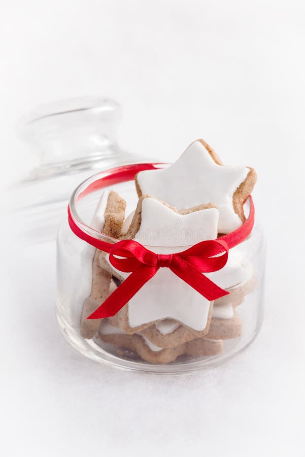 Sluit omhoog van een hoogtepunt van de glaskruik met koekjes van de Kerstmis de eigengemaakte ster over witte pluizige achtergron stock foto's Sluit omhoog van een hoogtepunt van de glaskruik met koekjes van de Kerstmis de eigengemaakte ster over witte pluizige achtergron stock foto's