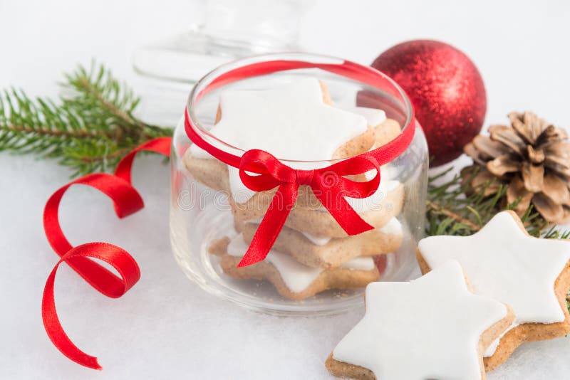 Sluit omhoog van een hoogtepunt van de glaskruik met koekjes van de Kerstmis de eigengemaakte ster over witte pluizige achtergron stock foto Sluit omhoog van een hoogtepunt van de glaskruik met koekjes van de Kerstmis de eigengemaakte ster over witte pluizige achtergron stock foto