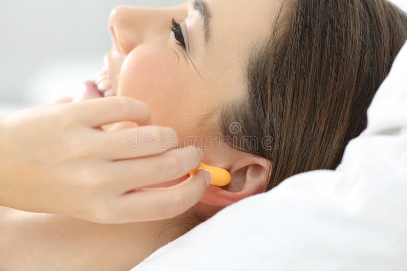 Sluit omhoog van een vrouwenhand zettend oorstoppen aan slaap