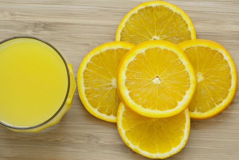 Sluit omhoog van gesneden sinaasappel en een volledig glas jus d'orange op houten oppervlakte stock foto Sluit omhoog van gesneden sinaasappel en een volledig glas jus d'orange op houten oppervlakte stock foto
