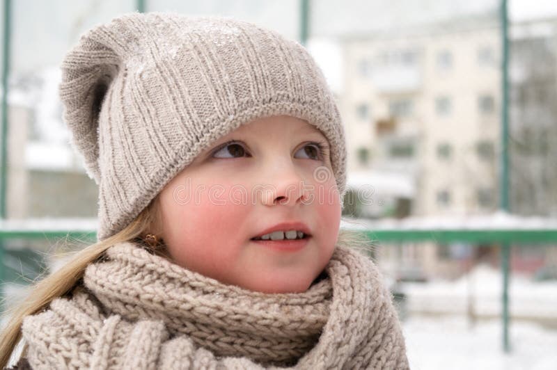 Sluit omhoog van glimlachend leuk meisje met de winter gebreide hoed Het openluchtschot met unfocused vage achtergrond royalty-vrije stock afbeelding Sluit omhoog van glimlachend leuk meisje met de winter gebreide hoed Het openluchtschot met unfocused vage achtergrond royalty-vrije stock afbeelding