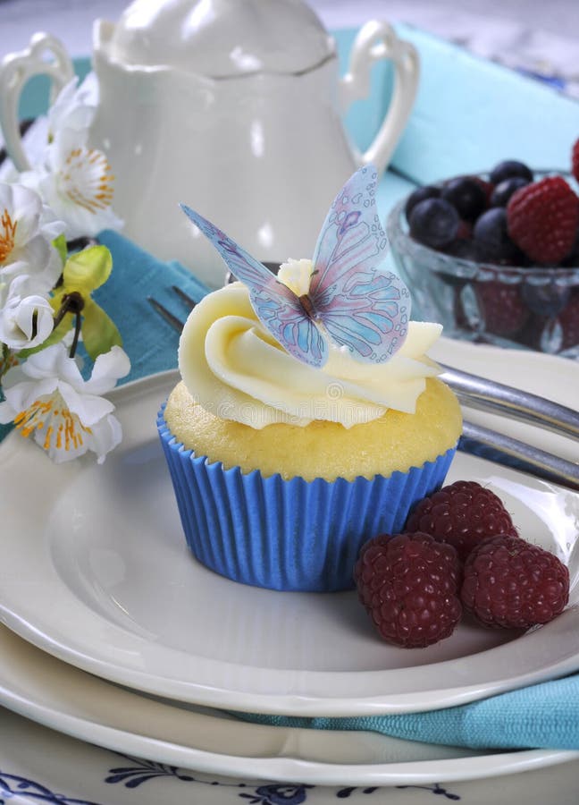 Sluit omhoog van heerlijke cupcake die met de decoratie van het vlinderwafeltje op uitstekend aqua blauw dienblad - verticaal pla