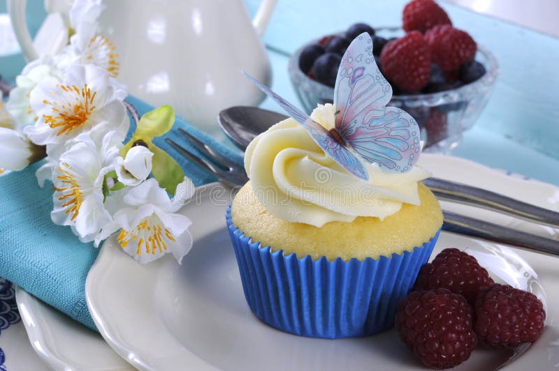 Sluit omhoog van heerlijke cupcake met de decoratie van het vlinderwafeltje bij het uitstekende aqua blauwe dienblad plaatsen