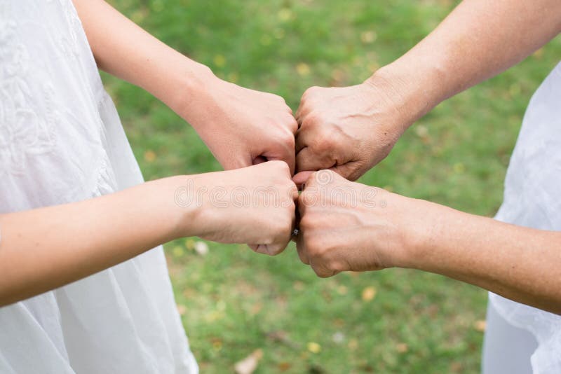 Sluit omhoog van hogere gevende de vuistbuil van de hand Aziatische vrouw aan handen jonge vrouwen bij openlucht stock foto Sluit omhoog van hogere gevende de vuistbuil van de hand Aziatische vrouw aan handen jonge vrouwen bij openlucht stock foto