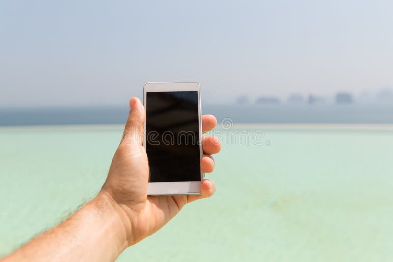 Sluit omhoog van mannelijke smartphone van de handholding op strand royalty-vrije stock afbeelding Sluit omhoog van mannelijke smartphone van de handholding op strand royalty-vrije stock afbeelding