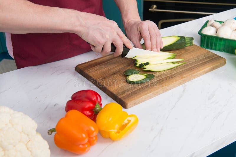 Sluit omhoog van mensen` s handen snijdend groene courgette De besnoeiingscourgette van mensen` s handen met wit mes Sluit omhoog royalty-vrije stock foto's Sluit omhoog van mensen` s handen snijdend groene courgette De besnoeiingscourgette van mensen` s handen met wit mes Sluit omhoog royalty-vrije stock foto's