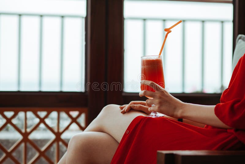 Sluit omhoog van vrouw in rode kleding met rode cocktail met oranje stro in handen Mooi meisje in het rode kleding drinken royalty-vrije stock afbeelding Sluit omhoog van vrouw in rode kleding met rode cocktail met oranje stro in handen Mooi meisje in het rode kleding drinken royalty-vrije stock afbeelding