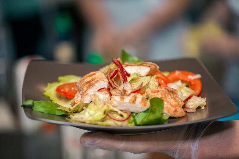 Sluit omhooggaande en selectieve nadruk die van handen Caesar-salade in restaurant of eetkamer in gezond voedselconcept houden