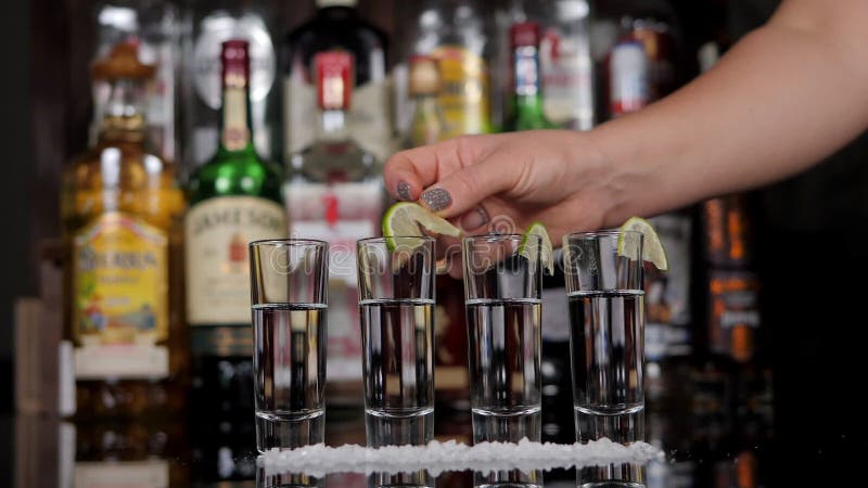Sluiting van een barman die kalkplakjes op een glas met tequila zet.