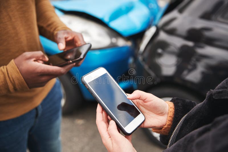 Sluiting van twee automobilisten die na een auto hun verzekeringsgegevens op mobiele telefoon ruilen stock foto Sluiting van twee automobilisten die na een auto hun verzekeringsgegevens op mobiele telefoon ruilen stock foto