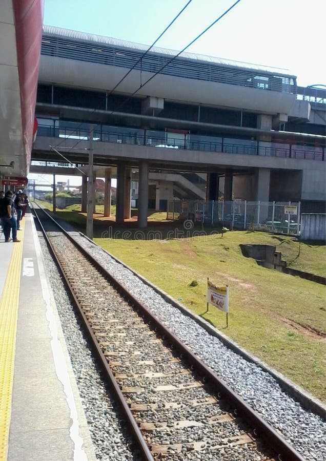 Railway platform leading to a station with a modern, elevated structure stock images