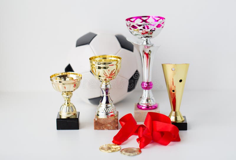 Slut upp av fotbollbollen, guld- koppar och medaljer royaltyfri bild Slut upp av fotbollbollen, guld- koppar och medaljer royaltyfri bild