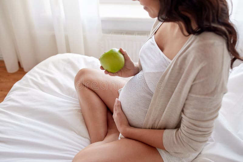 Slut upp av gravida kvinnan som hemma äter äpplet fotografering för bildbyråer Slut upp av gravida kvinnan som hemma äter äpplet fotografering för bildbyråer