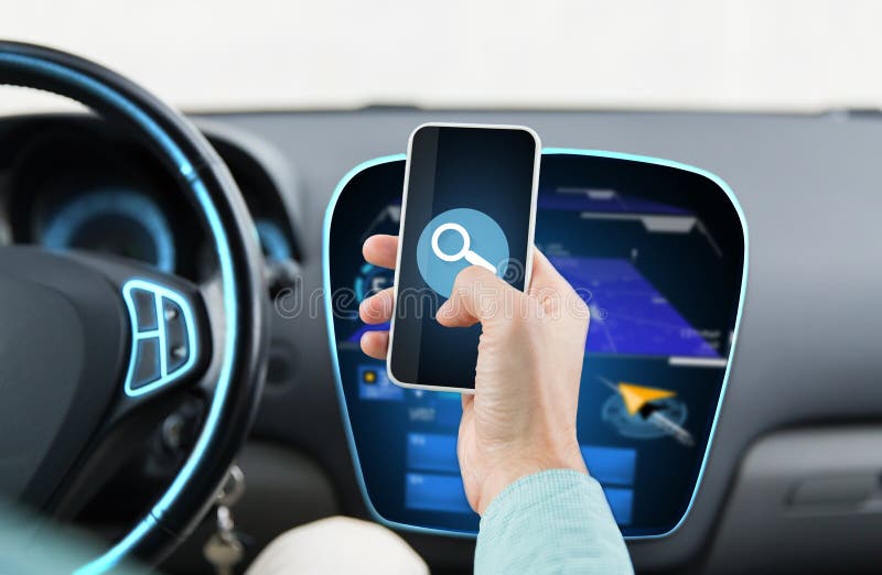 Transport, business trip, technology and people concept - close up of young man hand driving car and holding smartphone with lens icon on screen. Transport, business trip, technology and people concept - close up of young man hand driving car and holding smartphone with lens icon on screen