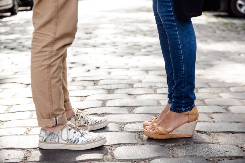 Slut upp av pars ben i keds som står på gatan royaltyfri foto Slut upp av pars ben i keds som står på gatan royaltyfri foto