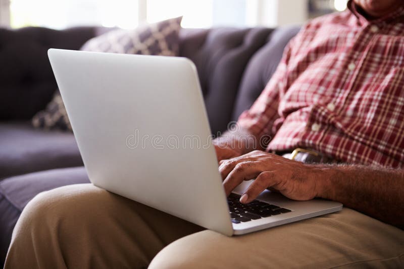 Slut upp av sammanträde för hög man på Sofa Using Laptop fotografering för bildbyråer Slut upp av sammanträde för hög man på Sofa Using Laptop fotografering för bildbyråer