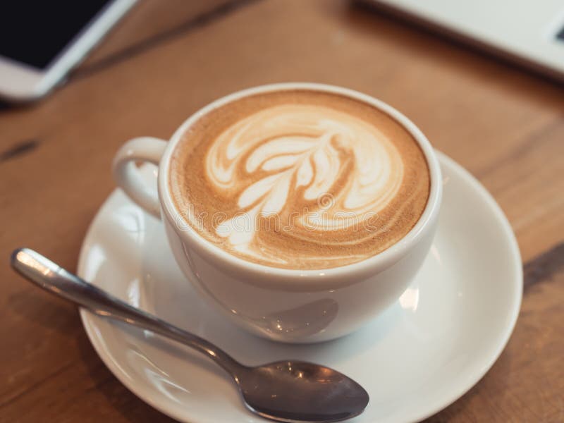 Slut upp koppen för vitt kaffe med lattekonst på trätabellen på coffee shop arkivfoton