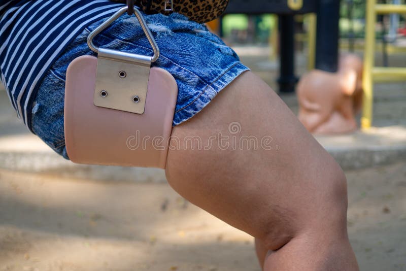 Slutet upp de fylliga benkvinnalåren bär kort jeans som sitter på gungastolar Visar muskeln, fett och cellulite runt om royaltyfria bilder Slutet upp de fylliga benkvinnalåren bär kort jeans som sitter på gungastolar Visar muskeln, fett och cellulite runt om royaltyfria bilder