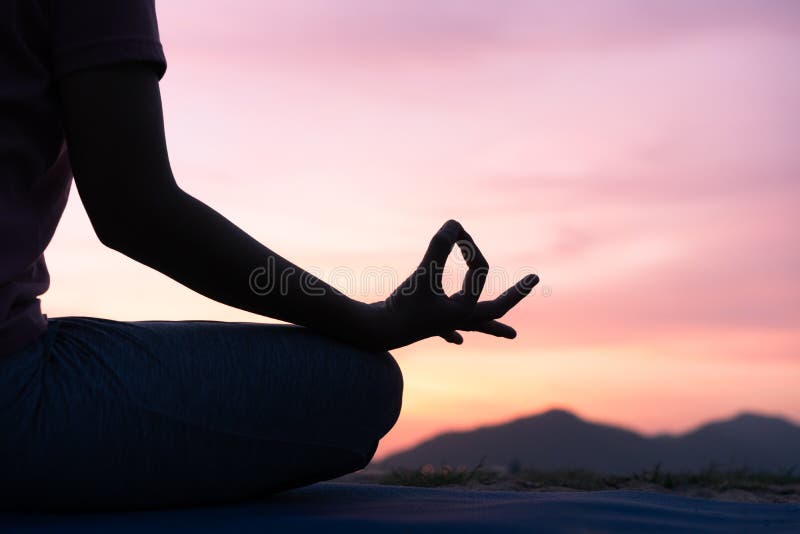 Slutet upp hand- och halvakropp av den vård- kvinnan sitter i lotusblomma, yoga sompositionen i den övande yogan för solnedgången arkivbild