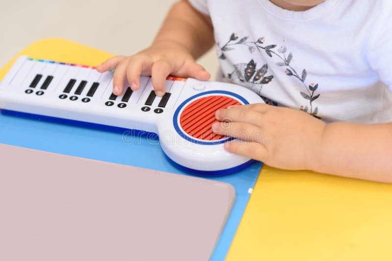 Slutet upp sm? h?nder spelar p? ett leksakpiano fotografering för bildbyråer Slutet upp sm? h?nder spelar p? ett leksakpiano fotografering för bildbyråer