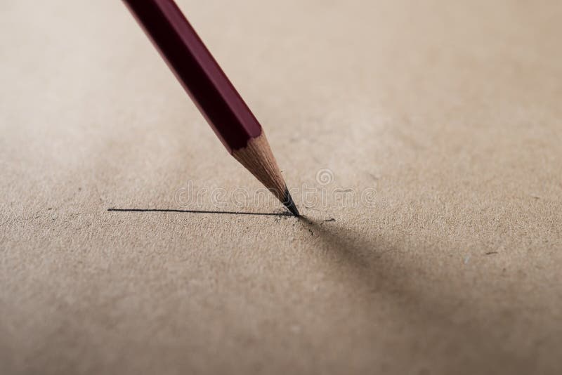 Close up sharpen pencil with line on blurred brown paper background low key tone. Close up sharpen pencil with line on blurred brown paper background low key tone