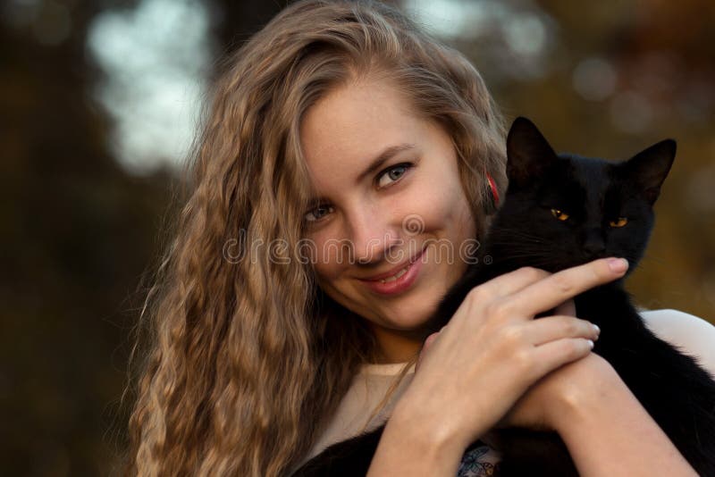 Sly, beau, espiègle, délicat, adroit, caressent et ont tenu le chat noir Animaux familiers d'amour de fille L'animal familier est images libres de droits Sly, beau, espiègle, délicat, adroit, caressent et ont tenu le chat noir Animaux familiers d'amour de fille L'animal familier est images libres de droits
