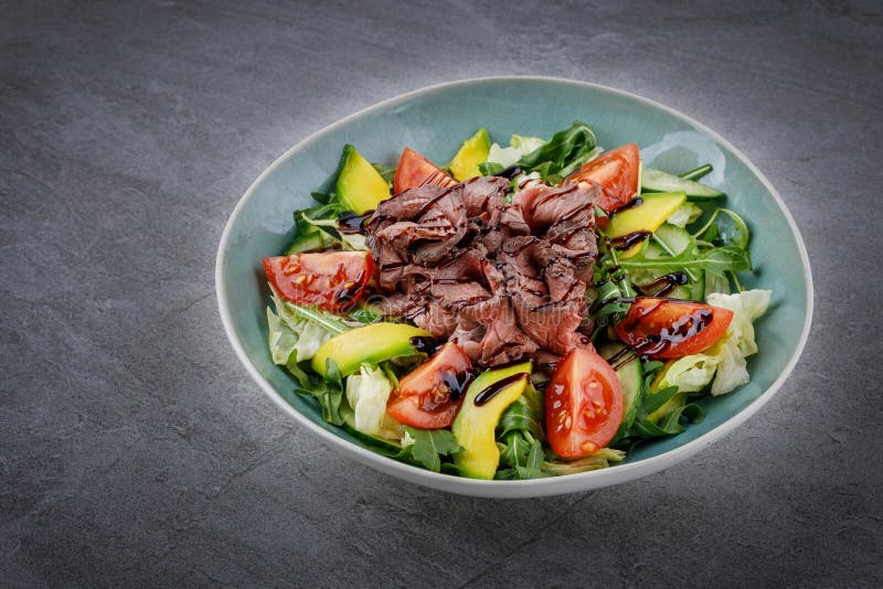 Tasty salad - roasted veal loin, avocado, boiled eggs and fresh vegetables on stone table. Tasty salad - roasted veal loin, avocado, boiled eggs and fresh vegetables on stone table