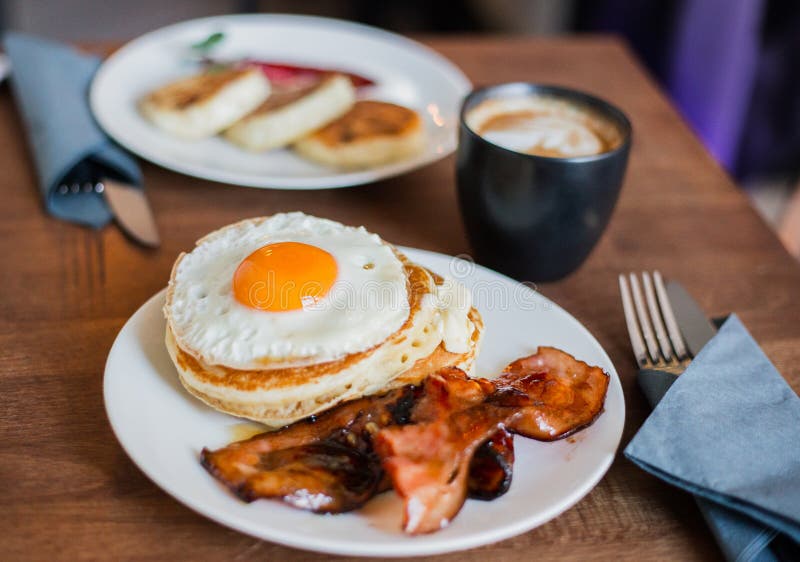 Smakelijk ontbijt met pannekoeken, gebraden ei, koffie en bacon stock afbeelding Smakelijk ontbijt met pannekoeken, gebraden ei, koffie en bacon stock afbeelding