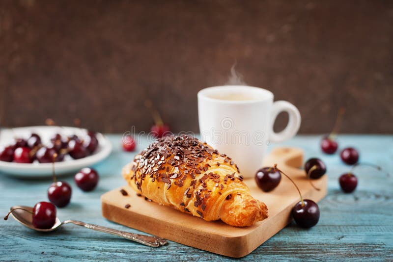 Smakelijk ontbijt met verse croissant, koffie en kersen op een houten lijst royalty-vrije stock fotografie Smakelijk ontbijt met verse croissant, koffie en kersen op een houten lijst royalty-vrije stock fotografie