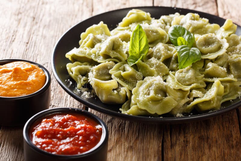 Tasty spinach green cappelletti, ravioli, tortellini with cheese, basil, ketchup, mustard close-up on the table. horizontal. Tasty spinach green cappelletti, ravioli, tortellini with cheese, basil, ketchup, mustard close-up on the table. horizontal