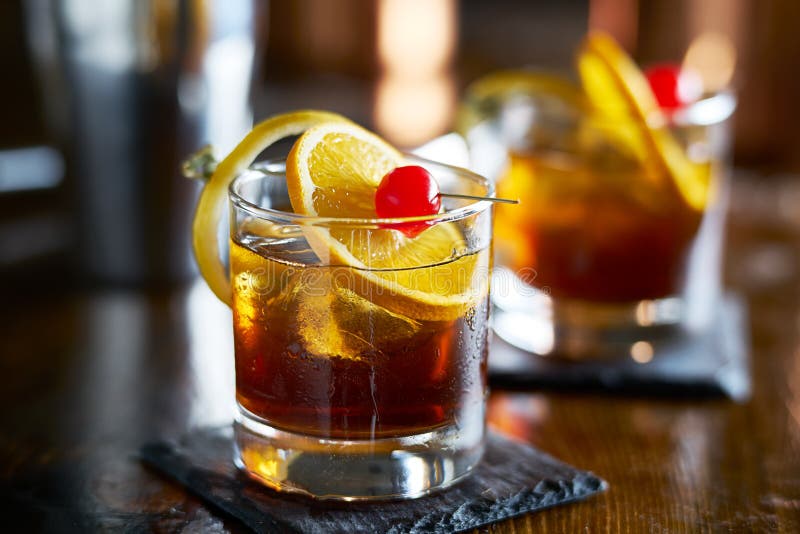 Smaklig alkoholiserad gammalmodig coctail med den orange skivan, körsbäret och citronskalgarnering arkivbilder Smaklig alkoholiserad gammalmodig coctail med den orange skivan, körsbäret och citronskalgarnering arkivbilder