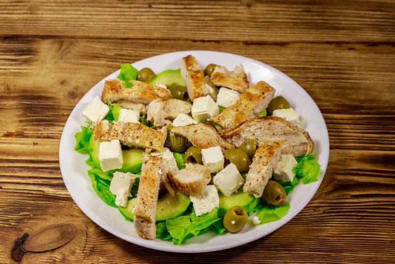 Smaklig sallad med stekt kycklingbröstet, gröna oliv, fetaost, avokadot, grönsallat och olivolja på trätabellen arkivfoto Smaklig sallad med stekt kycklingbröstet, gröna oliv, fetaost, avokadot, grönsallat och olivolja på trätabellen arkivfoto