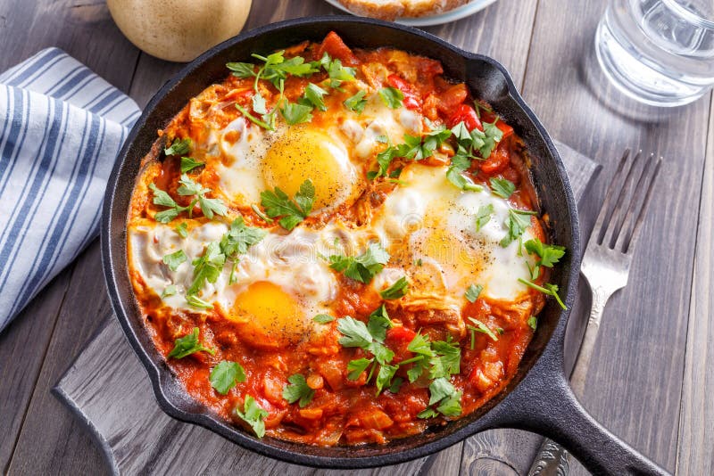 Tasty and Helthy Shakshuka in a Cast-Iron Skillet. Eggs Poached in Spicy Tomato Pepper Sauce. Top View. Tasty and Helthy Shakshuka in a Cast-Iron Skillet. Eggs Poached in Spicy Tomato Pepper Sauce. Top View.