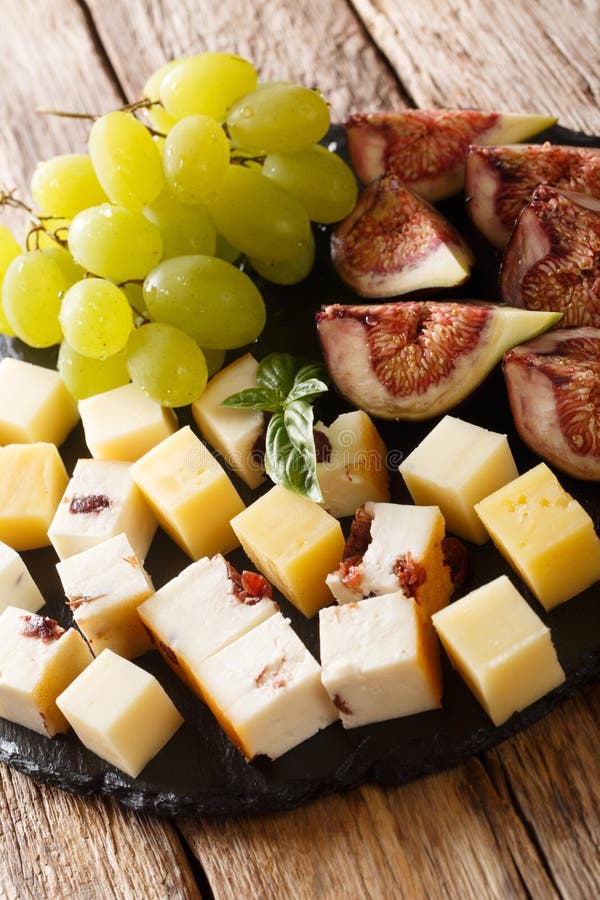 Smakowita antipasti zakąska różnorodny ser, winogrona i figi w górę, dalej krytykujemy deskę pionowo zdjęcia stock Smakowita antipasti zakąska różnorodny ser, winogrona i figi w górę, dalej krytykujemy deskę pionowo zdjęcia stock
