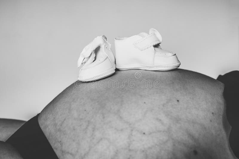 Small Baby Boots on Mother Stomach, Black and White Stock Image Image