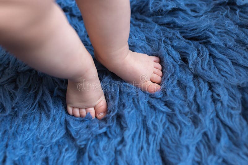 Small Baby Feet Doing the First Step on the Blue Carpet Stock Photo