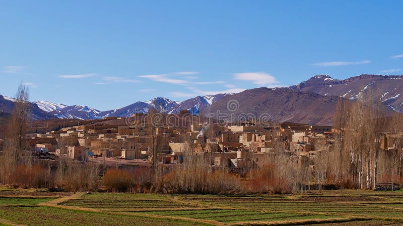 Small Berber village located in Atlas Mountains near Imilchil, Morocco, Africa with green fields and snow-capped mountains.