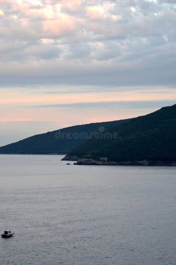 A Small Boat Near Forest-covered Hills Under a Dawn Sky Stock Photo ...