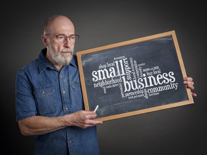 Small business concept - word cloud on a blackboard. Held by a senior man