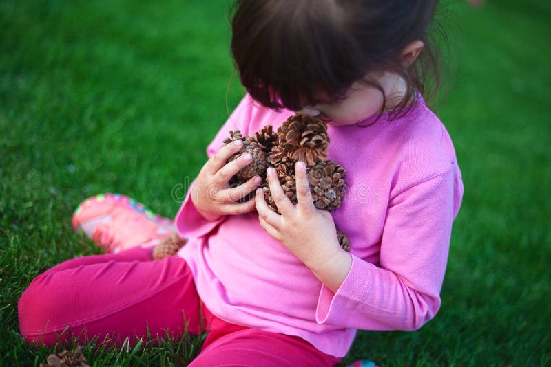 Small Child With a Lot of Pine Cones