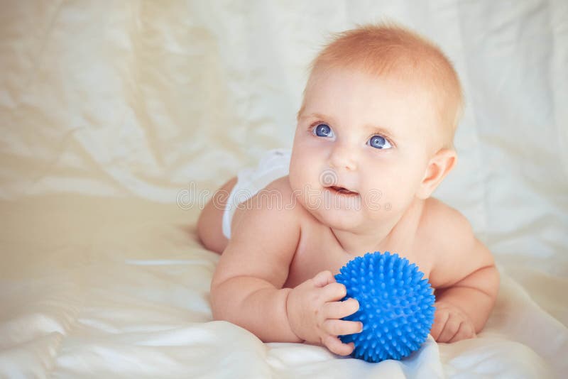 Small child lying on stomach and holding ball for massage