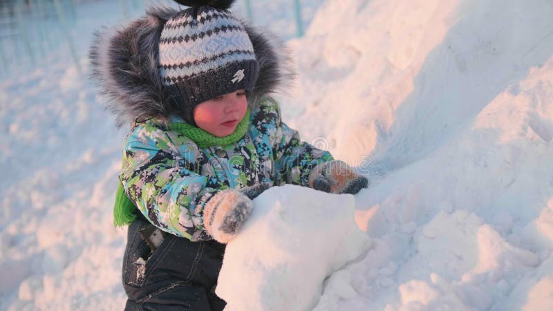 A small child is playing in a winter Park with snow. A Sunny winter day. Fun and games in the fresh air. stock photo A small child is playing in a winter Park with snow. A Sunny winter day. Fun and games in the fresh air. stock photo