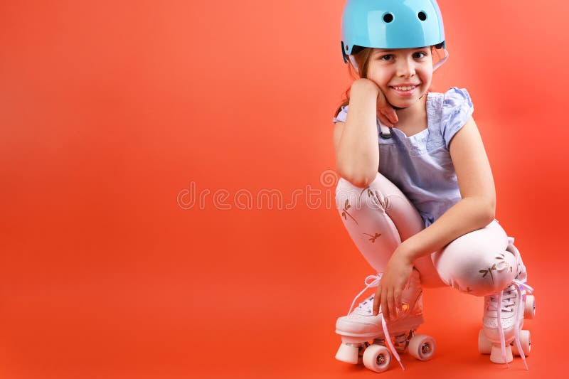 A small child with roller skates and a blue helmet demonstrates positive emotions. A girl of 7 years old poses and