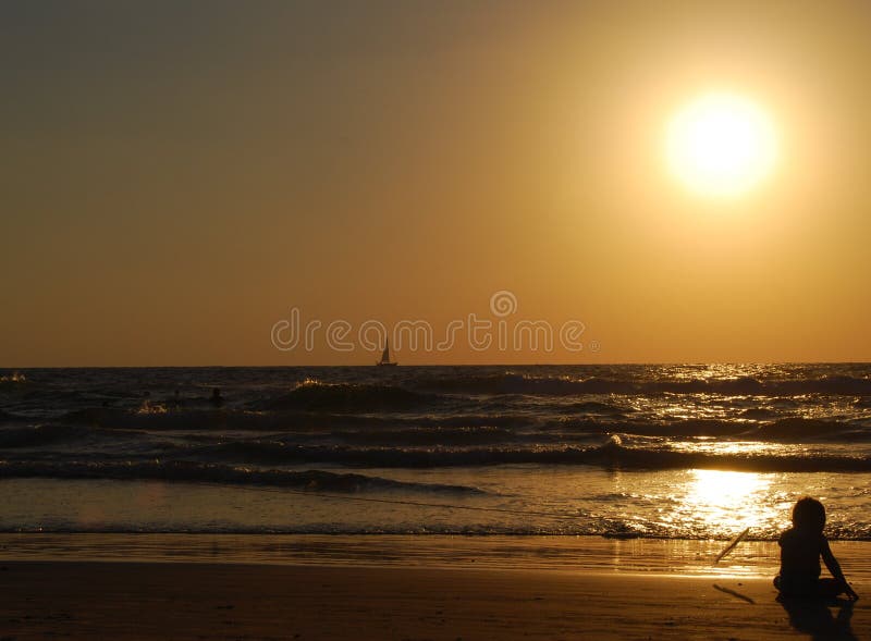 Kleines Kind auf das Meer, auf sand und im Sonnenuntergang.