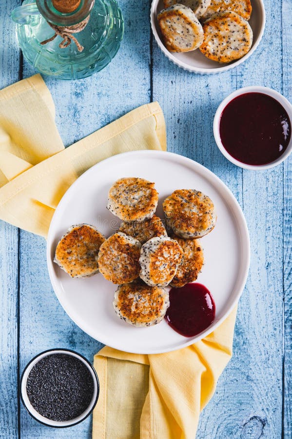 Small cottage cheese pancakes with poppy seeds on a plate on the table top and vertical view stock photography